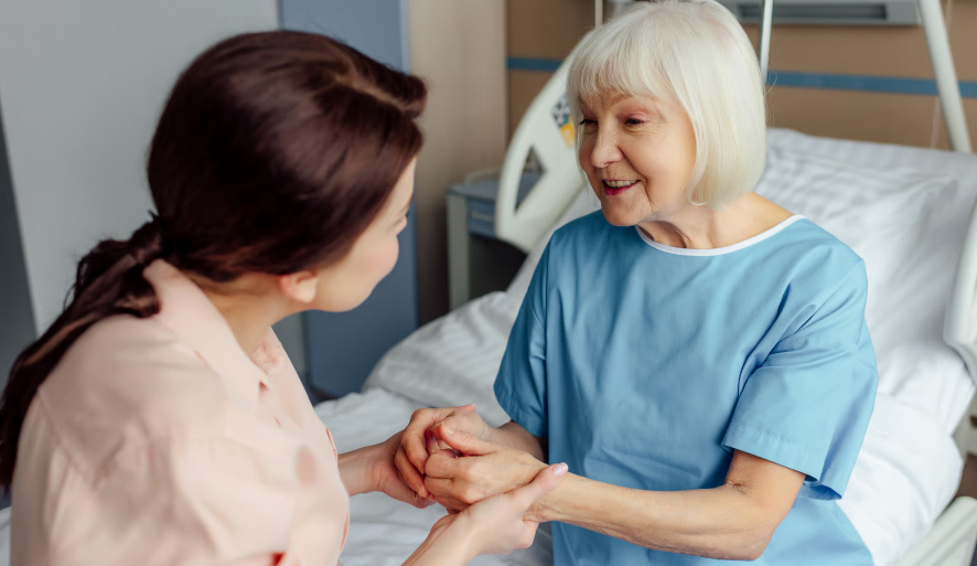 A senior male hospice medical director in a white lab coat speaking with a nurse and caregiver, representing clinical leadership in Dallas-Fort Worth hospice care.